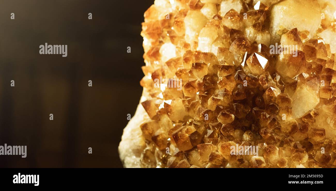 Zitrinsteinmakrokristalle mit geringer Schärfentiefe. Gelber Quarz auf dunklem Hintergrund, Banner. Stockfoto