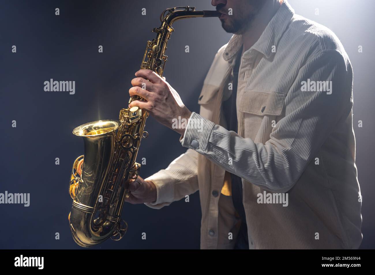 Männlicher Musiker auf der Bühne spielt das Saxophon dunkel mit Rauch. Stockfoto