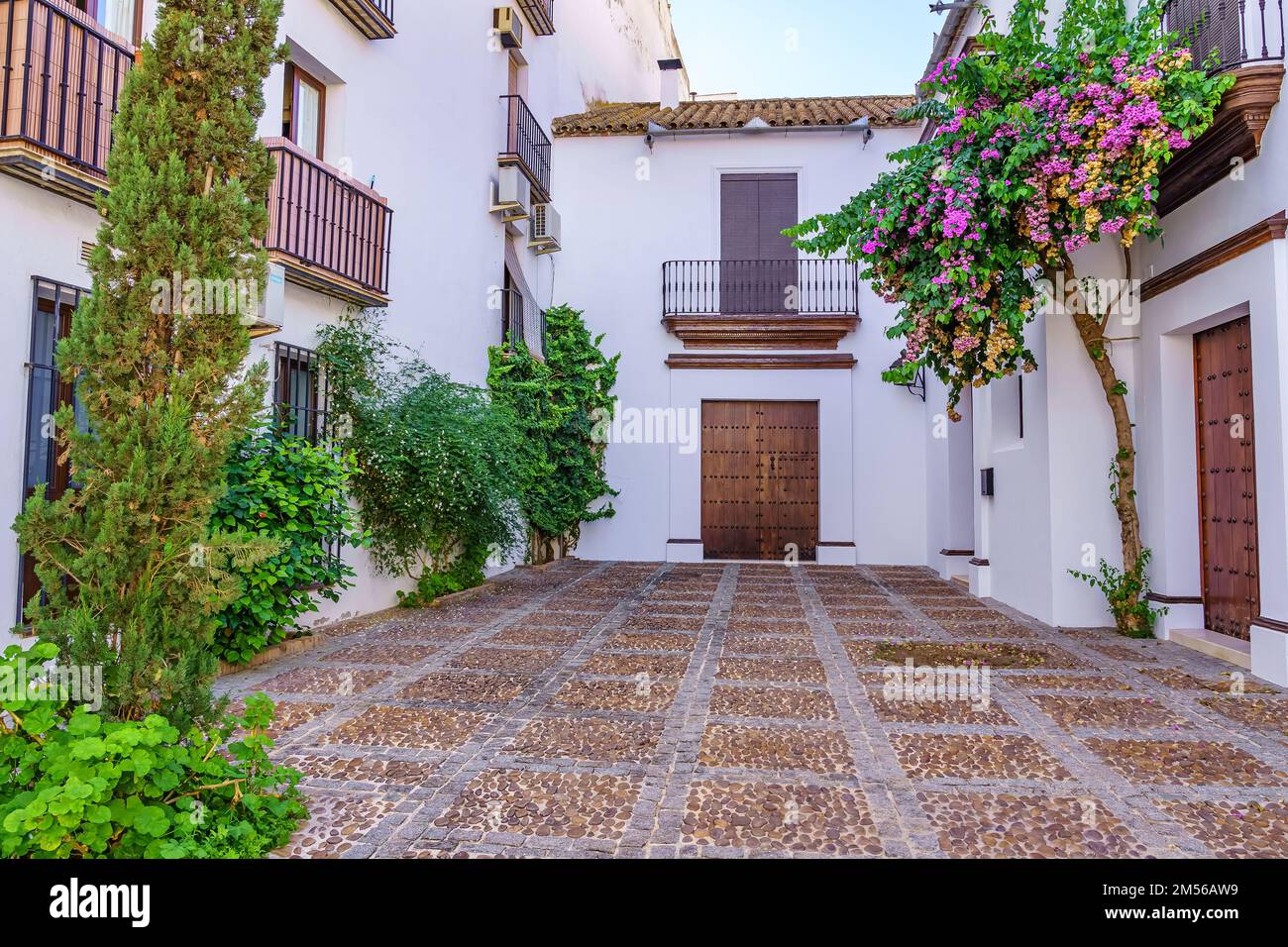 Typisch andalusische Terrasse mit weiß bemalten Häusern, alten Holztüren und blühenden Pflanzen an den Fassaden. Stockfoto