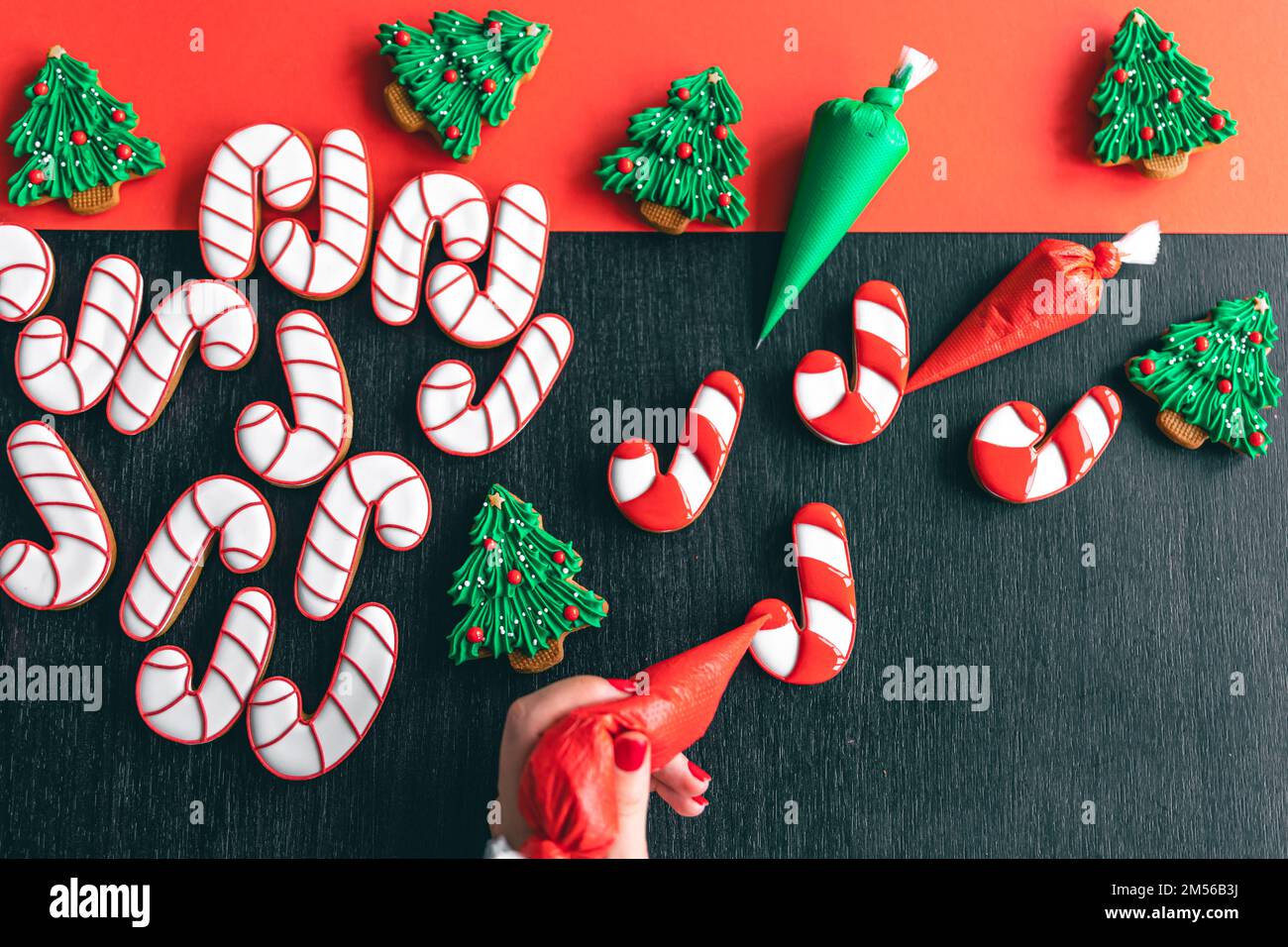 Eine Frau bedeckt sich mit dem Glasur von Weihnachts-Lebkuchen in Form von Süßigkeiten. Stockfoto