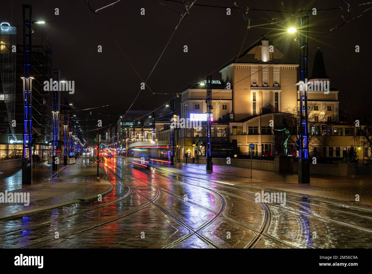 Lange Sicht auf Hämeenkatu vor der Dämmerung mit Lichtern, die von nassen Straßen in Tampere, Finnland, reflektiert werden Stockfoto