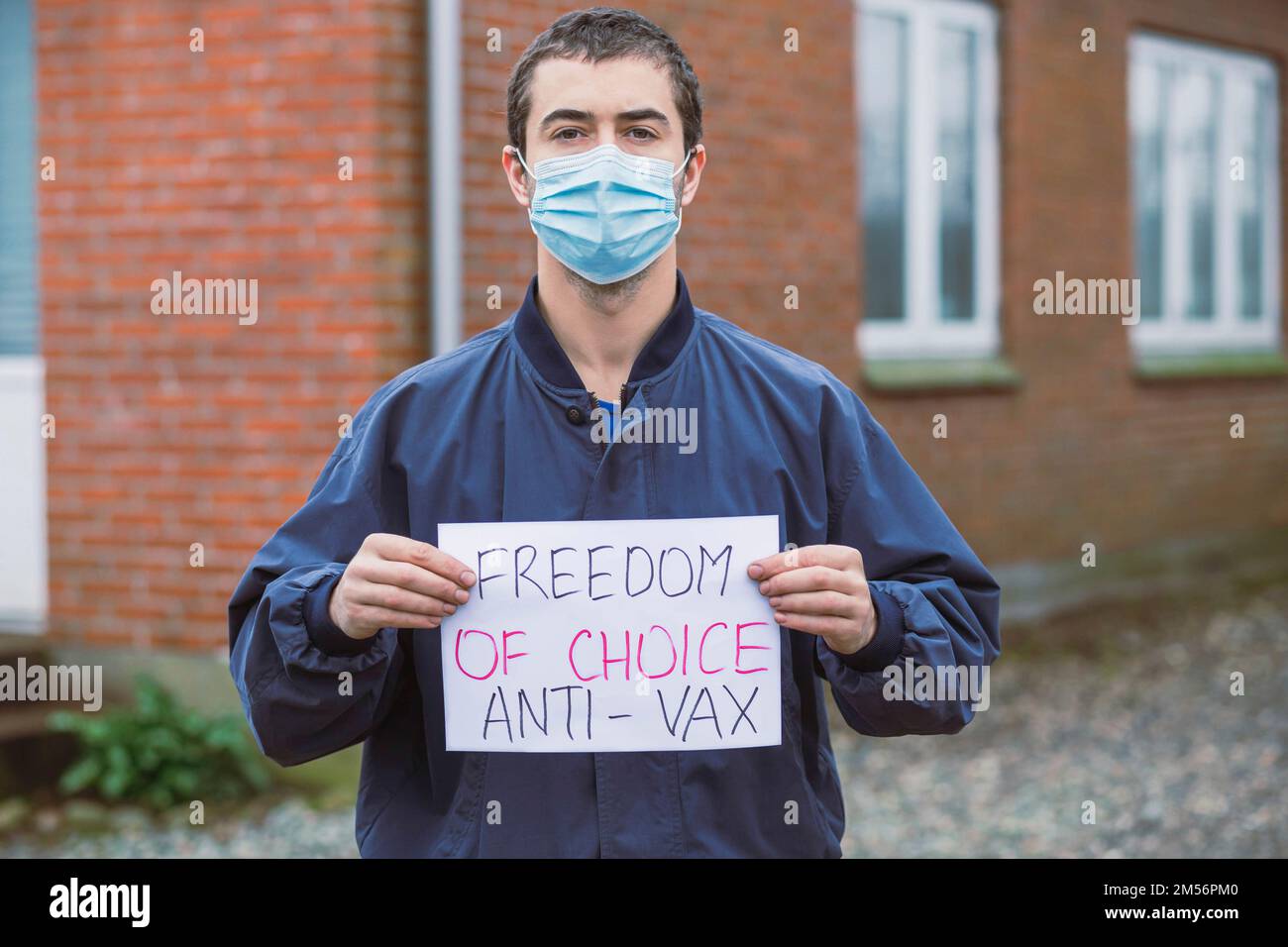 Ein Mann mit einem Anti-Impfposter in der Nähe seines Hauses Stockfoto