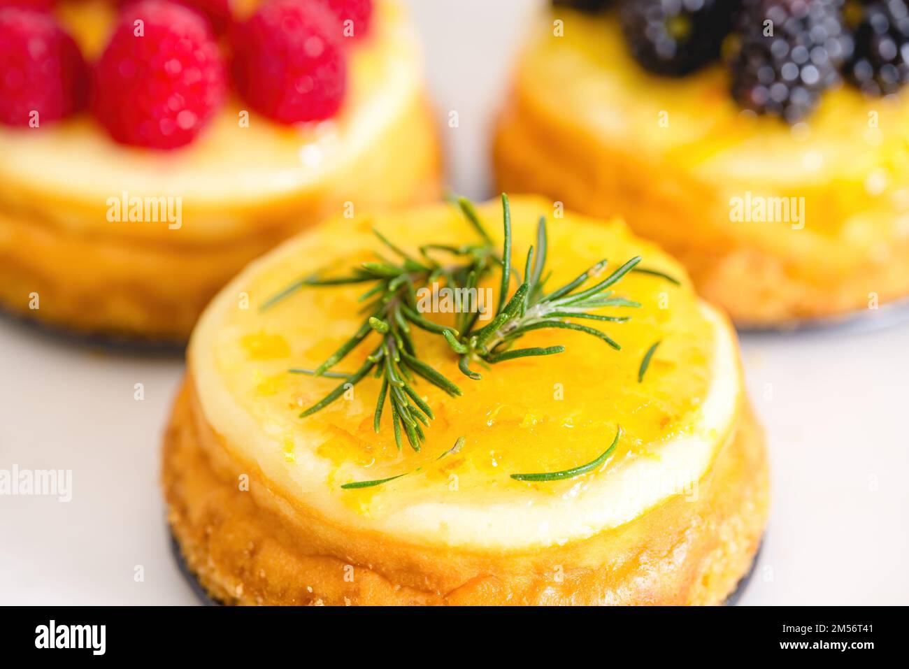 Mini-Käsekuchen mit Gelee und Rosematie Nahaufnahme auf dem Küchentisch. Köstliches Dessert, perfekte Kombination aus süßen und würzigen Geschmacksrichtungen, Hausmannskost Stockfoto
