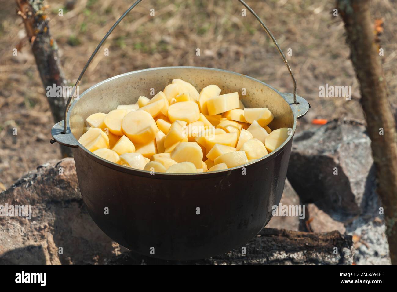 Kartoffelscheiben in einem Kessel. Essen auf offenem Feuer zubereiten, Campingmahlzeit Stockfoto