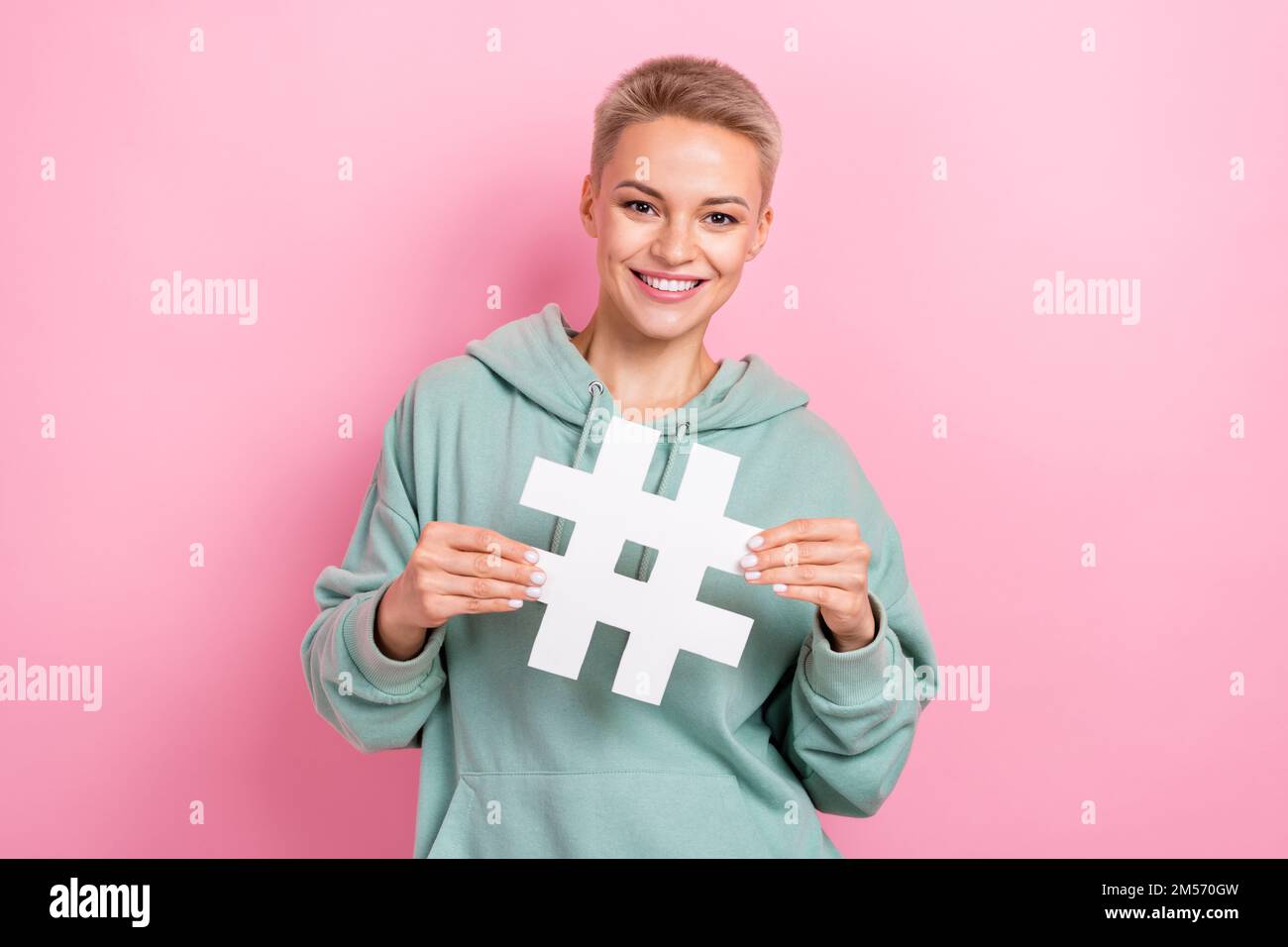 Foto eines hübschen jungen Mädchens mit Hashtag Symbol Influencer Marketer gekleidet stilvoll Khaki Look isoliert auf pinkfarbenem Hintergrund Stockfoto
