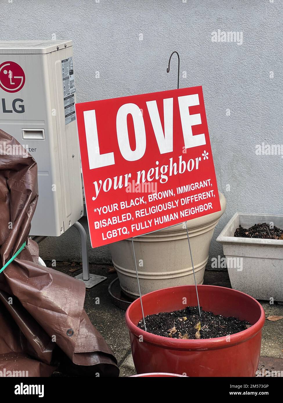 Das Schild „Love Your Neighbor“ betont, dass es alle Menschen außerhalb eines Heims in Brooklyn, New York, bedeutet. Stockfoto