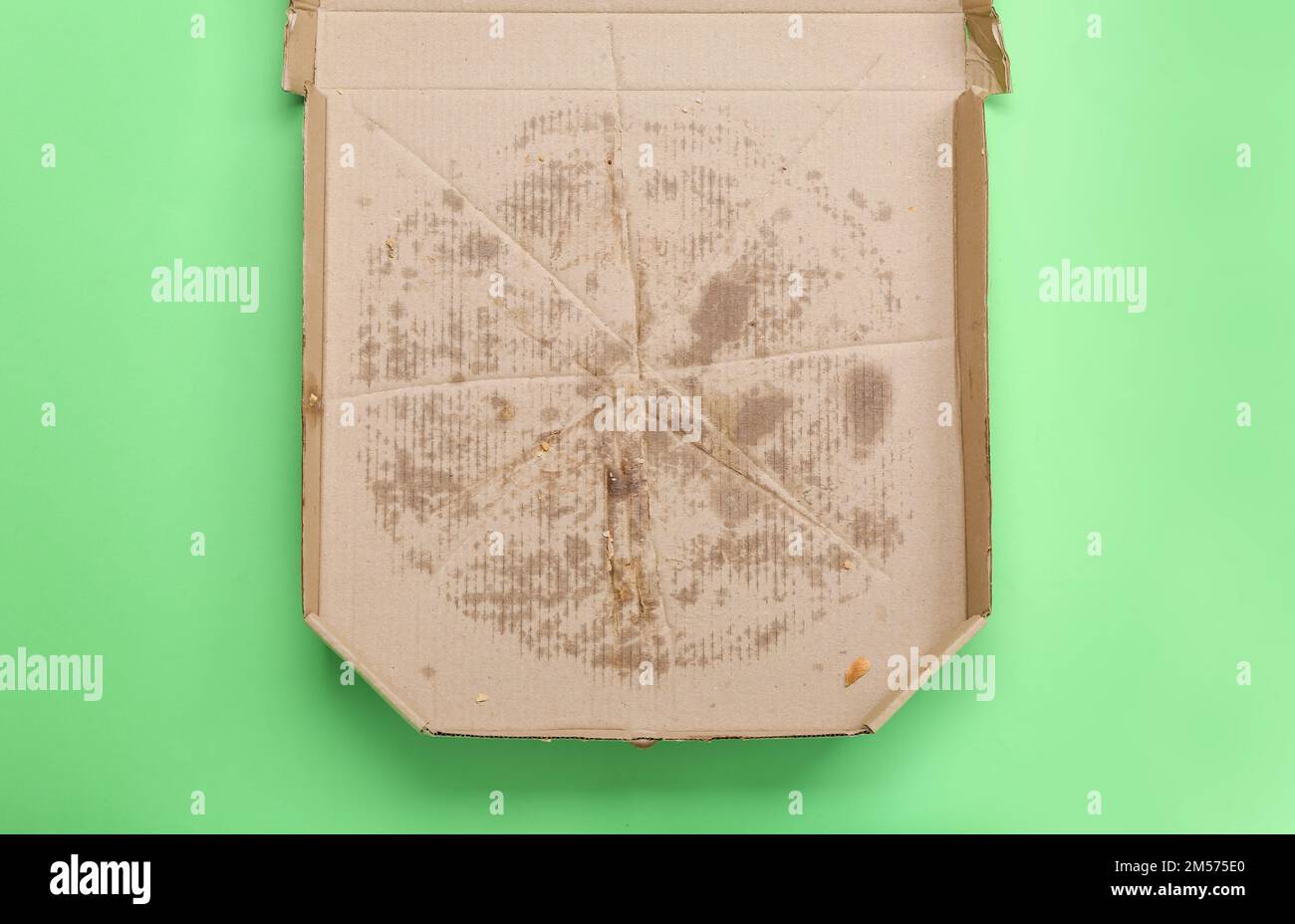 Leere fettige Pizza-Box auf grünem Hintergrund Stockfoto