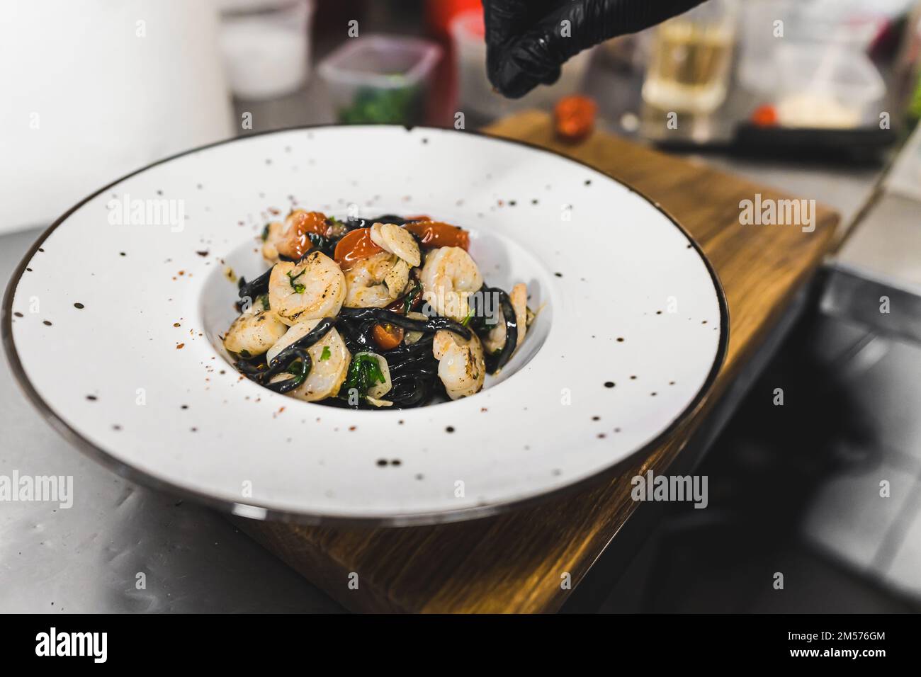 Verschiedene italienische Speisen. Schwarze Tagliolini-Pasta mit Garnelen. Koch-Dekorationsteller. Nahaufnahme im Innenbereich. Hochwertiges Foto Stockfoto