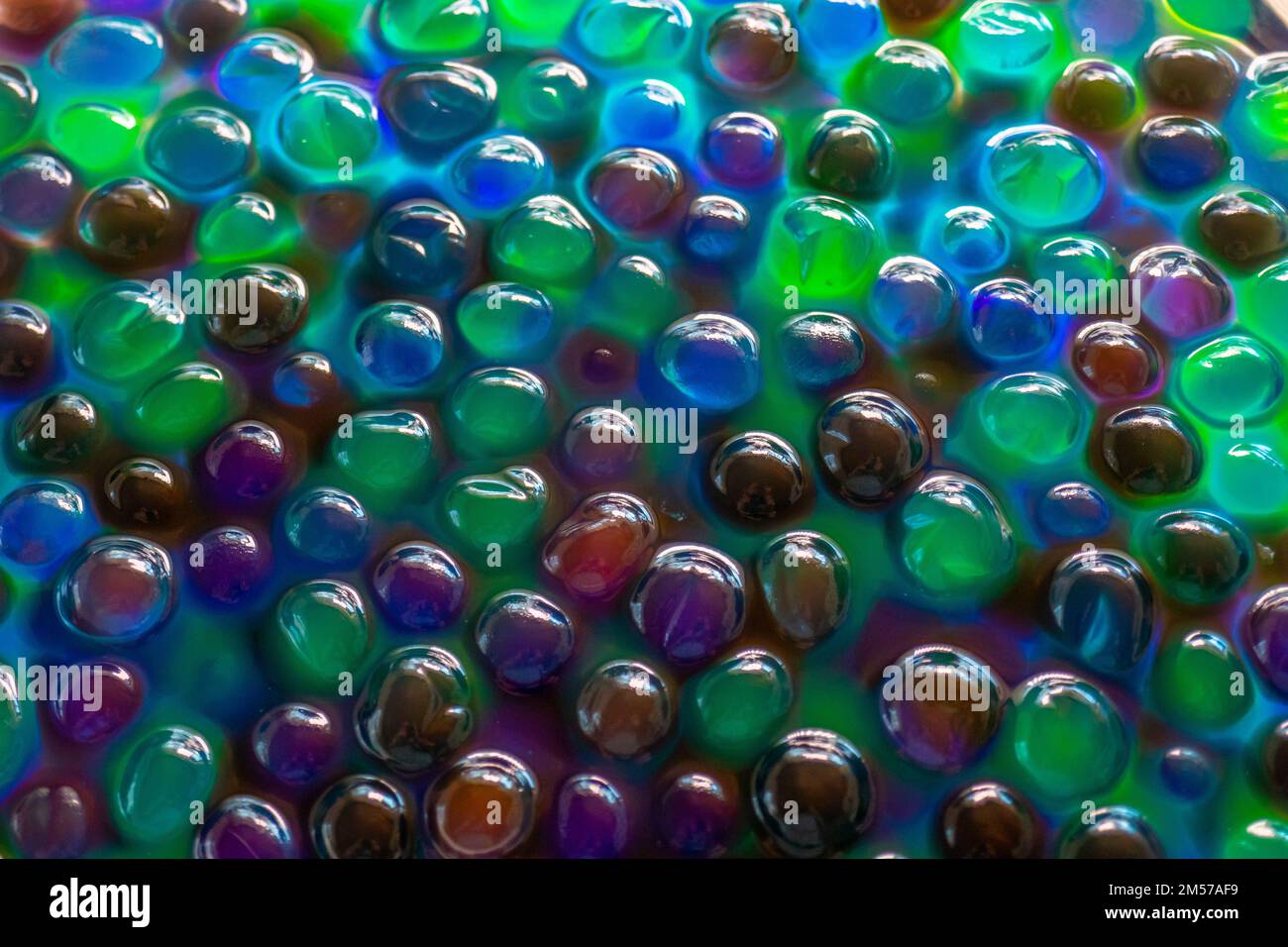 Hydrogelkugeln für Dekoration, Gartenarbeit und Luftbefeuchter. Hintergrund in kühlen Farben. Mehrfarbige Orbiz-Struktur. Stockfoto