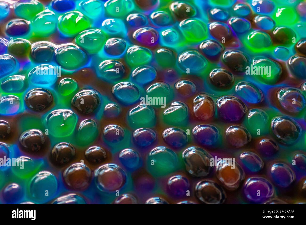 Orbiz-Bälle im Wasser. Hydrogel-Bälle für Dekoration, Gartenarbeit und Luftbefeuchter. Hintergrund in kühlen Farben. Mehrfarbige Orbiz-Textur. Stockfoto