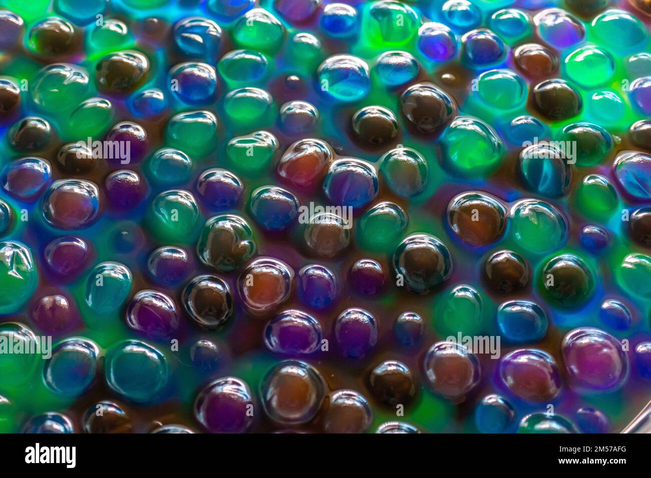 Hydrogel Orbeez Hintergrund. Blaue grüne Orbiz Bälle im Wasser. Hydrogel Bälle für Dekoration, Gartenarbeit und Luftbefeuchter. Hintergrund in kühlen Farben. Stockfoto