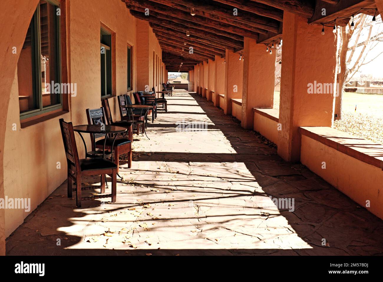 Eine Außenkolonnade mit leeren Tischen und Stühlen im historischen Wahrzeichen La Posada, einem historischen Harvey House Hotel in Winslow, Arizona. Stockfoto