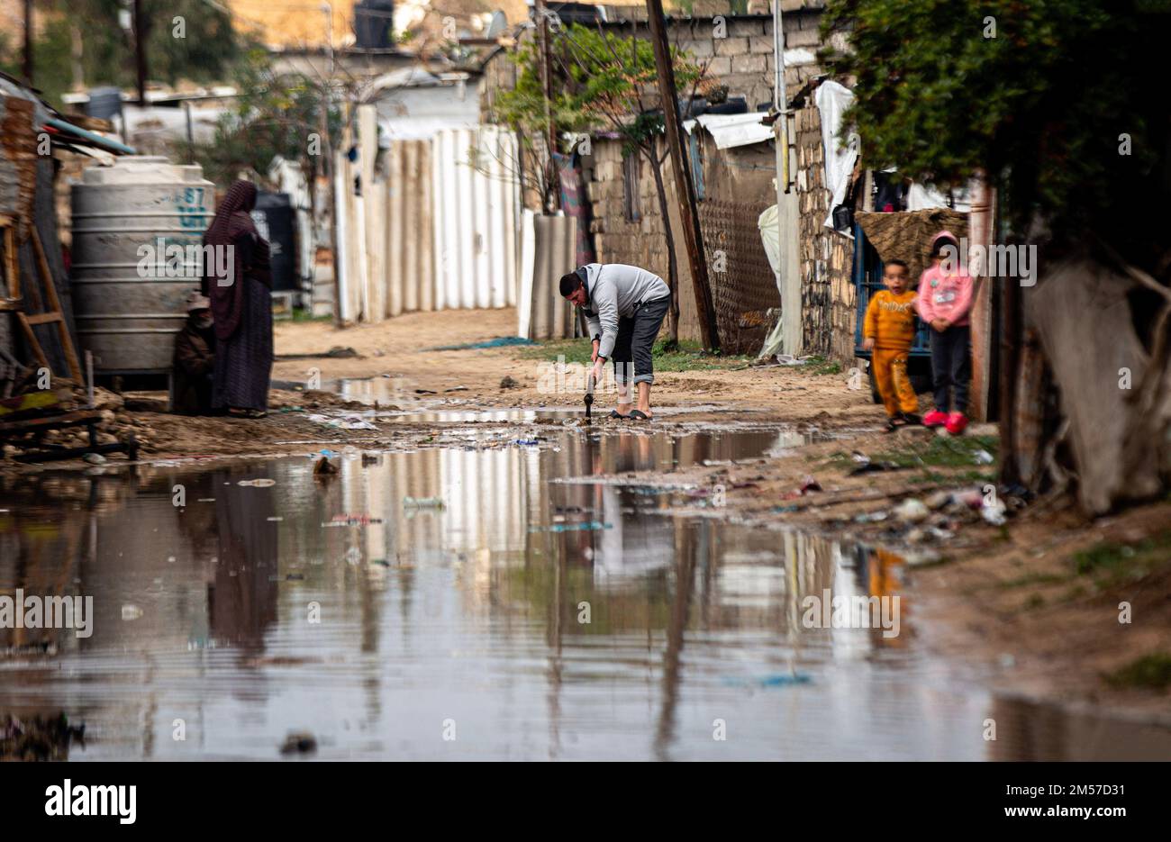 Gaza, Palästina. 26. Dezember 2022. Die Palästinenser stehen auf einer von Regenwasser überfluteten Straße in einem armen Viertel am Rande des Khan Yunis-Lagers im südlichen Gazastreifen. Kredit: SOPA Images Limited/Alamy Live News Stockfoto