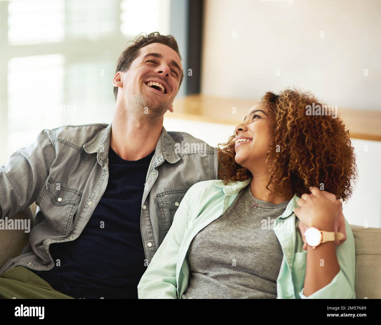 Das ist urkomisch. Ein liebevolles junges Paar, das zu Hause lacht. Stockfoto