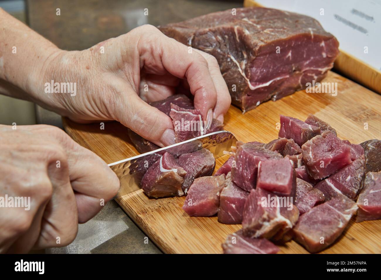 Der Küchenchef schneidet das Rindfleisch zum Kochen in Würfel Stockfoto