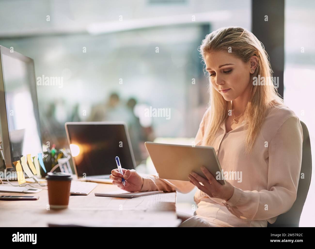 Sie nutzt Technologie bei ihrer täglichen Arbeit. Eine lächelnde junge Geschäftsfrau, die in einem Büro an einem digitalen Tablet arbeitet. Stockfoto