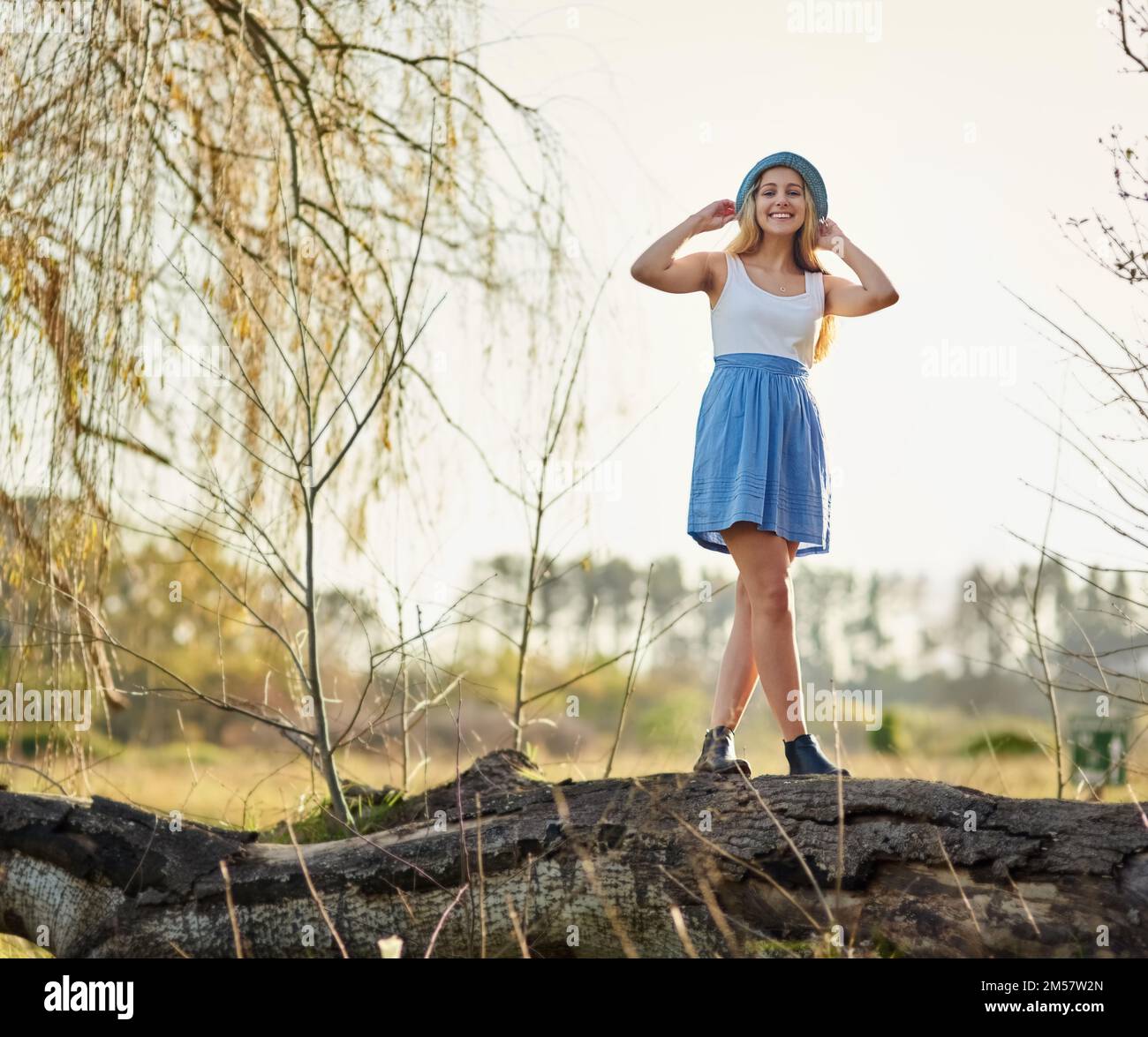 Nichts geht über das Aufwachen zum Gesang der Vögel. Eine junge Frau auf einem Baumstumpf auf dem Land. Stockfoto