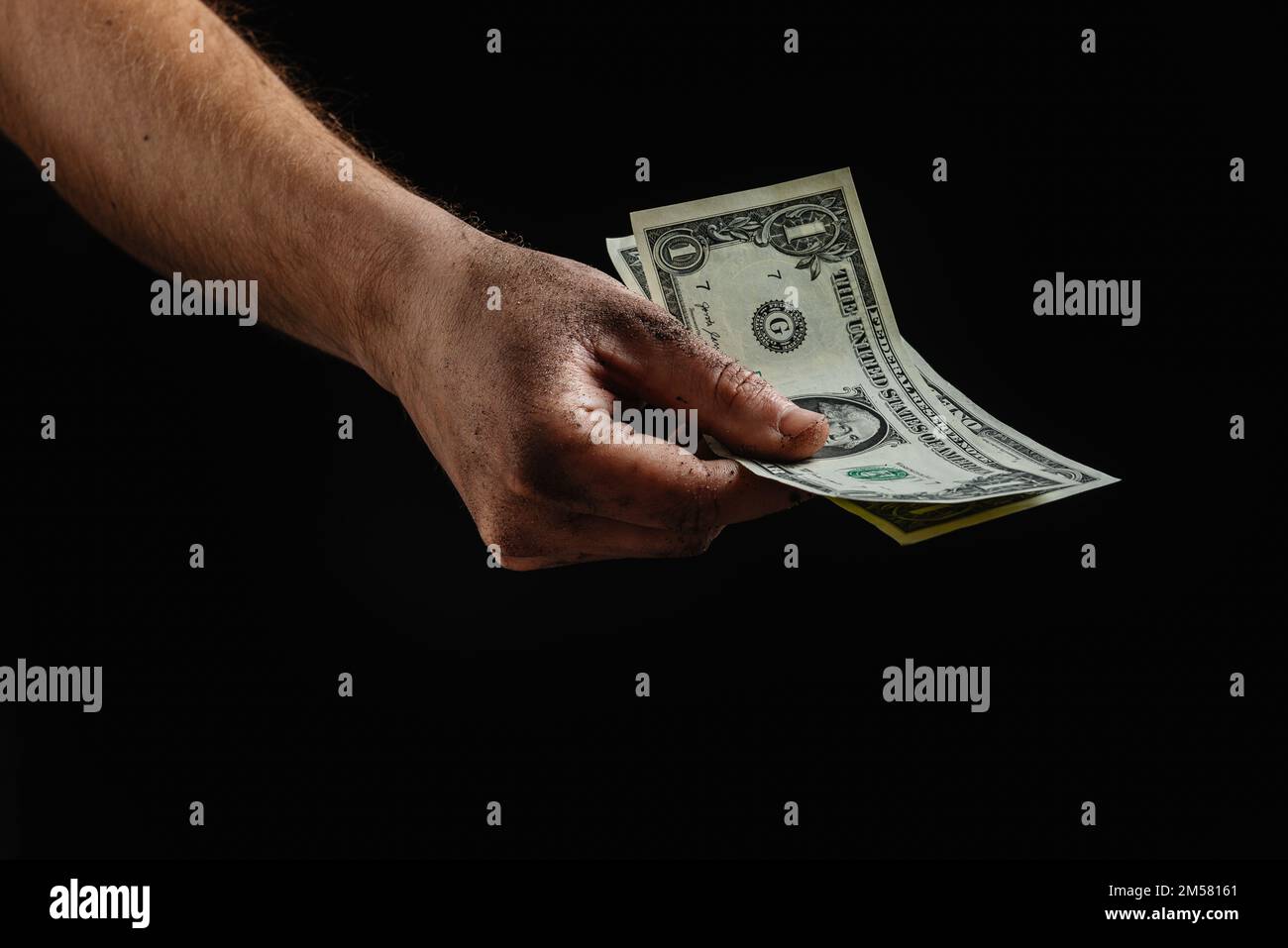 Das konzeptionelle Bild schmutziger Hände, die ein paar Dollar halten. Finanzkrise. Zusammenbruch der Wirtschaft. Stockfoto