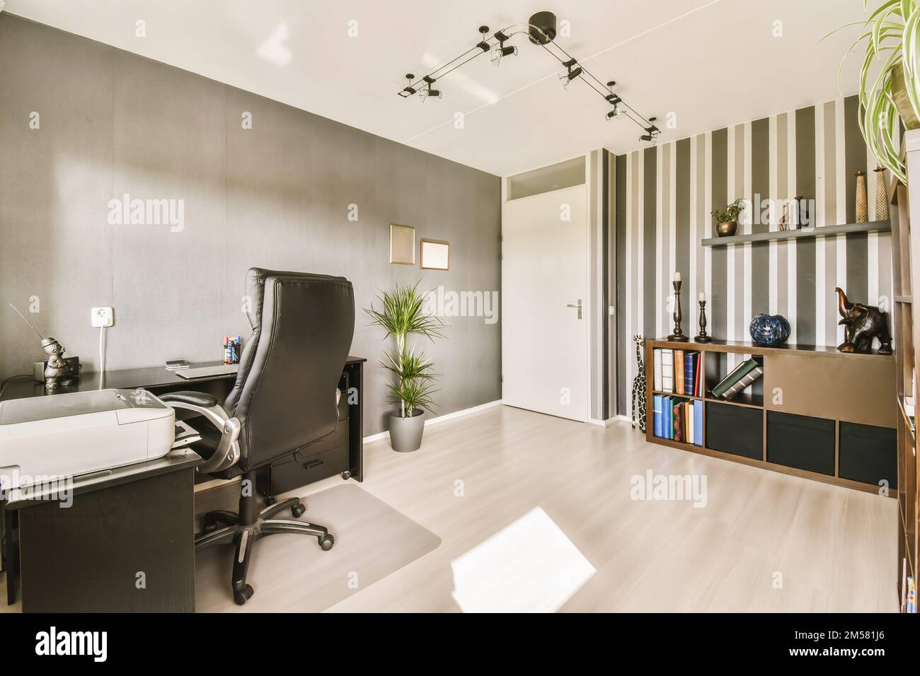 Ein Heimbüro mit Holzfußboden und grauen Tapeten an den Wänden und ein schwarzer Computertisch Stockfoto