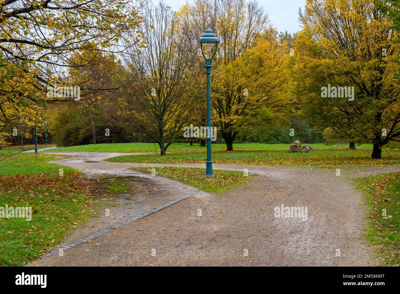 Pfad in einem Park um eine Lampe mit einer Abkürzung, die den bevorzugten Weg zeigt Stockfoto