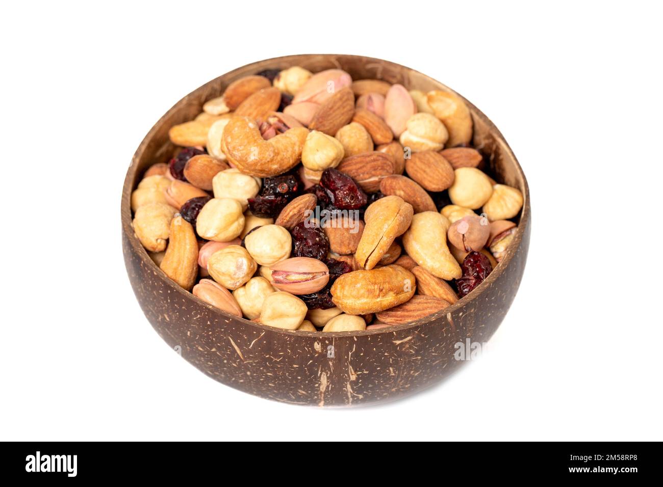 Gemischte Nüsse in Schüssel isoliert auf weißem Hintergrund. Nüsse, Cashews, Mandeln und Pistazien in einer Kokosnussschale. Schließen Stockfoto