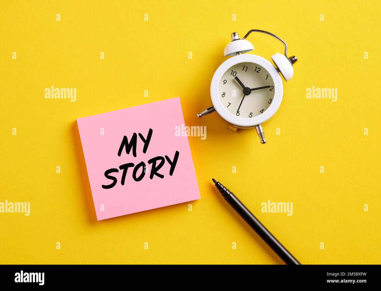 Meine Story auf pinkfarbenem Zettel mit Wecker und Stift. Persönliche Lebensgeschichte oder persönliche Karriere für das Geschäftskonzept. Stockfoto