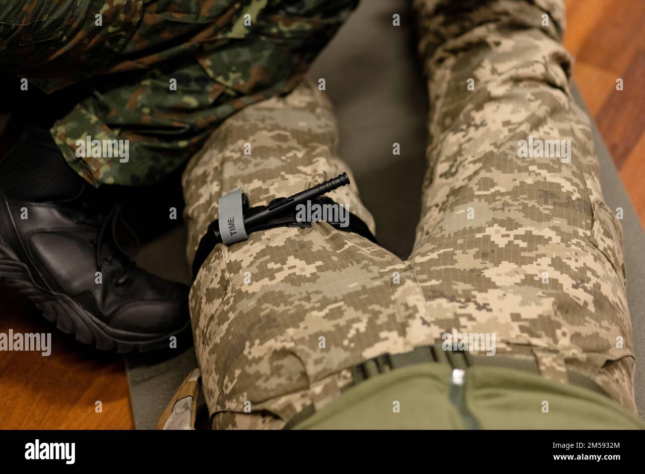 Ein Militär demonstriert einen Kampfschlauch, um Blut während der ersten Hilfe zu stoppen. Anweisungen für Kampftaktik-Ausrüstung. Stockfoto