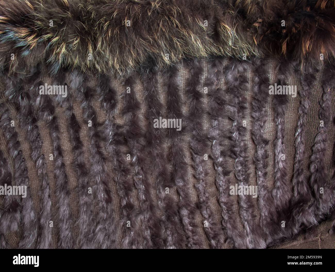 Hintergrund aus dunkelbraunem Fell und Wolle. Kombiniertes Pelzgestrickprodukt mit Einlagen aus Fuchswolle und Fell. Stockfoto