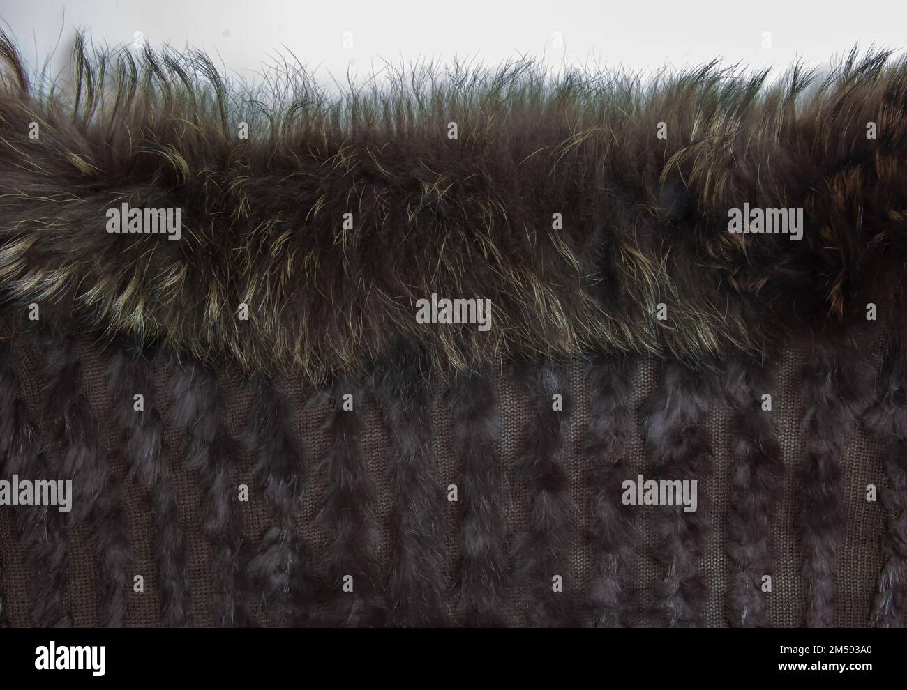 Hintergrund aus dunkelbraunem Fell und Wolle. Kombiniertes Pelzgestrickprodukt mit Einlagen aus Fuchswolle und Fell. Stockfoto