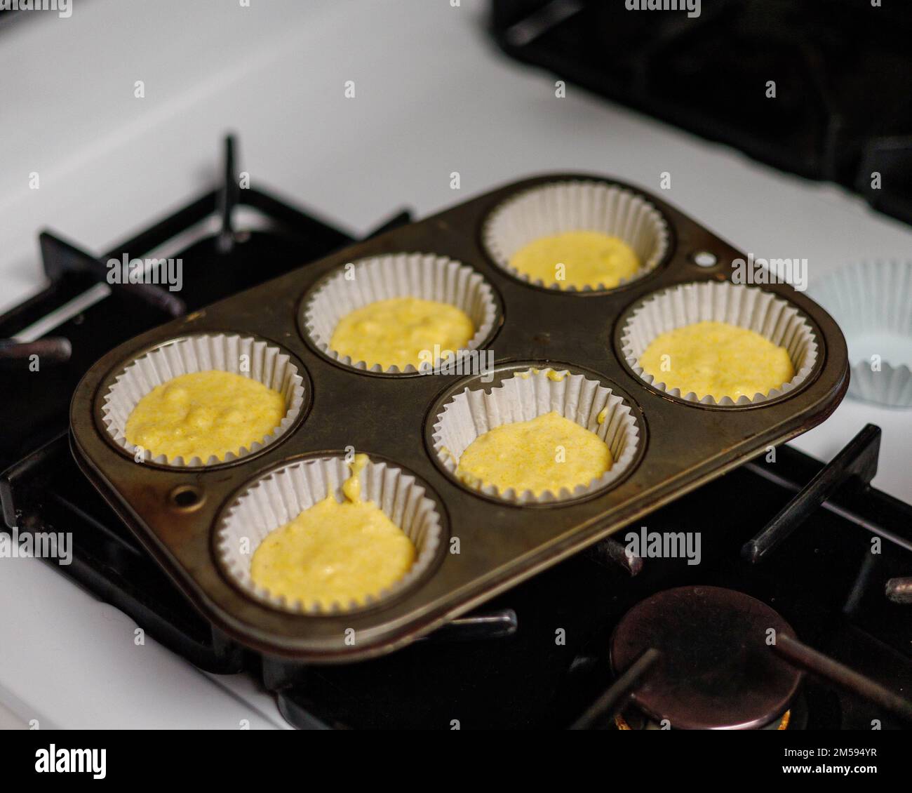 Ein Tablett mit normalem Maisbrotteig, in Cupcake-Papiere aufgetropft Stockfoto