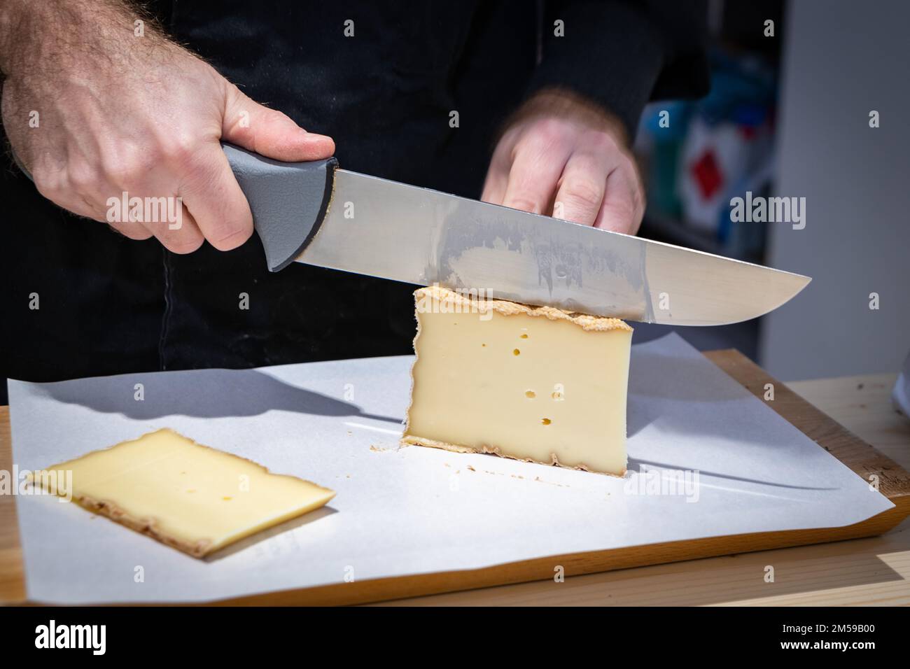 Juli 11 2022, Lyon, Frankreich : Ein Mann Schneidet einen Teil der Vacherin Fribourgeois mit einem Draht, einem berühmten schweizer Käse, ab Stockfoto
