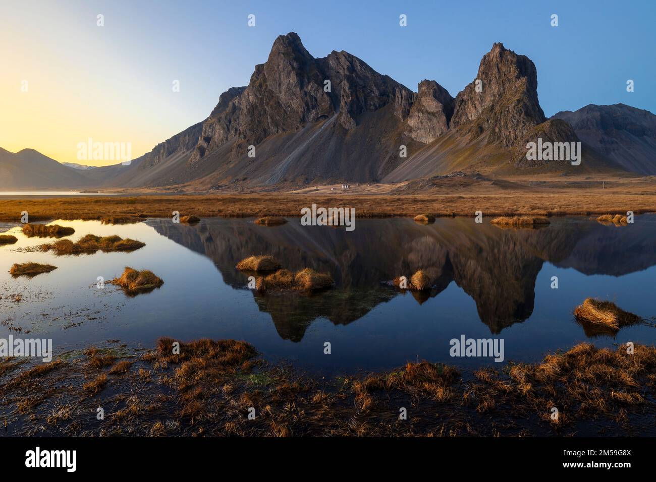 Ein Mann beobachtet, wie das Eystrahorn bei Sonnenuntergang reflektiert wird, Krossanesfjall, Djupivogur, Austurland, Island, Nordeuropa Stockfoto