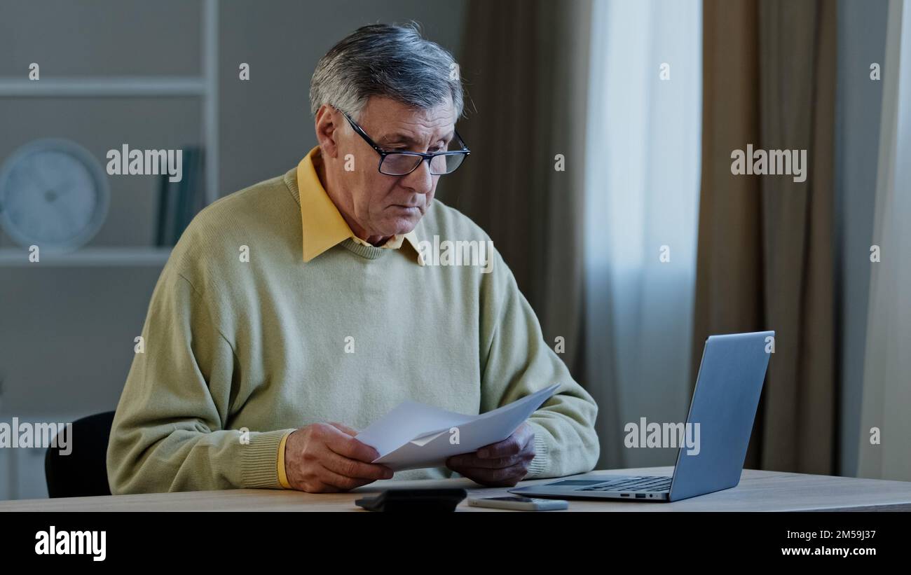 Seriöser alter, weißer, grauhaariger Geschäftsmann, 70s männlicher, älterer, älterer Unternehmer, sitzt am Tisch mit Papierproblemen mit Dokumenten Stockfoto