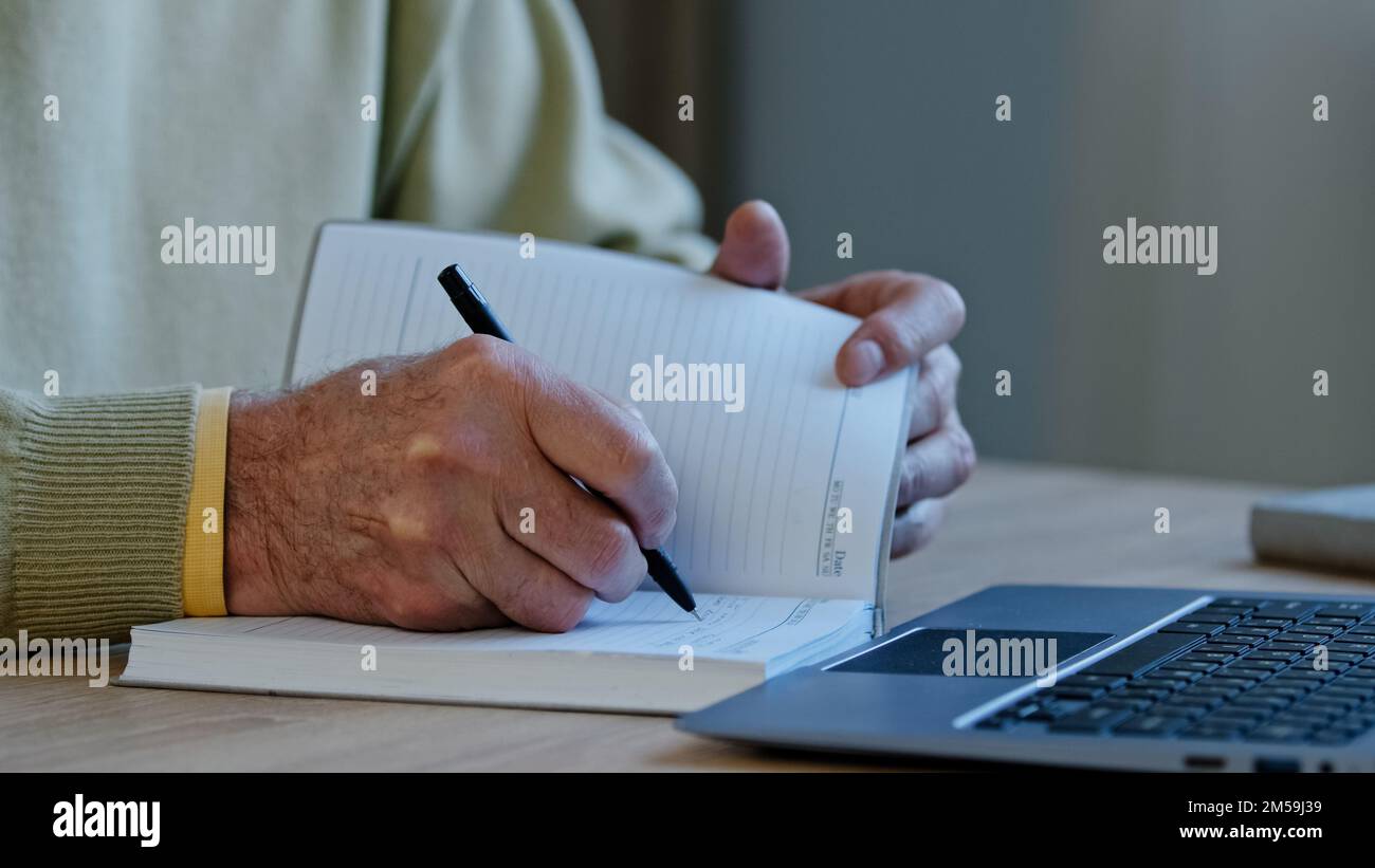 Ein nicht wiedererkennbarer, reifer Mann sitzt am Arbeitsplatz und bereitet einen Vortrag für Schüler vor. Ein Autor erstellt handgeschriebene Texte, mit denen Rentner arbeiten Stockfoto