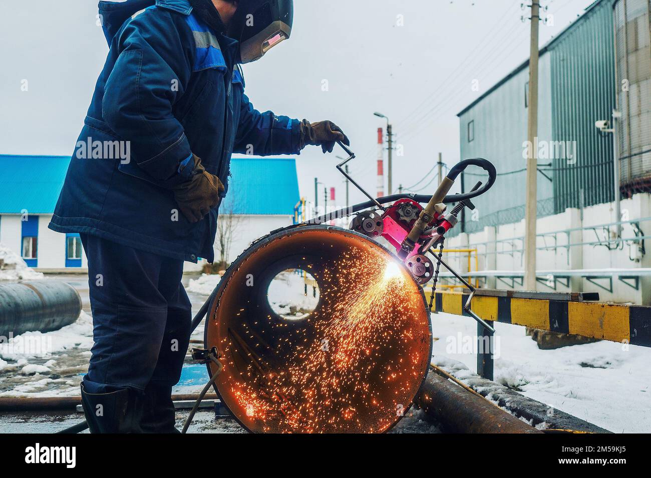 Funktionierender Schweißer schneidet Metall und Funken fliegen. Gasschneiden von grossen Rohrdurchmessern mit Acetylen und Sauerstoff. Industrielle Metallzerspanung in der Öl- und Gasindustrie. Stockfoto