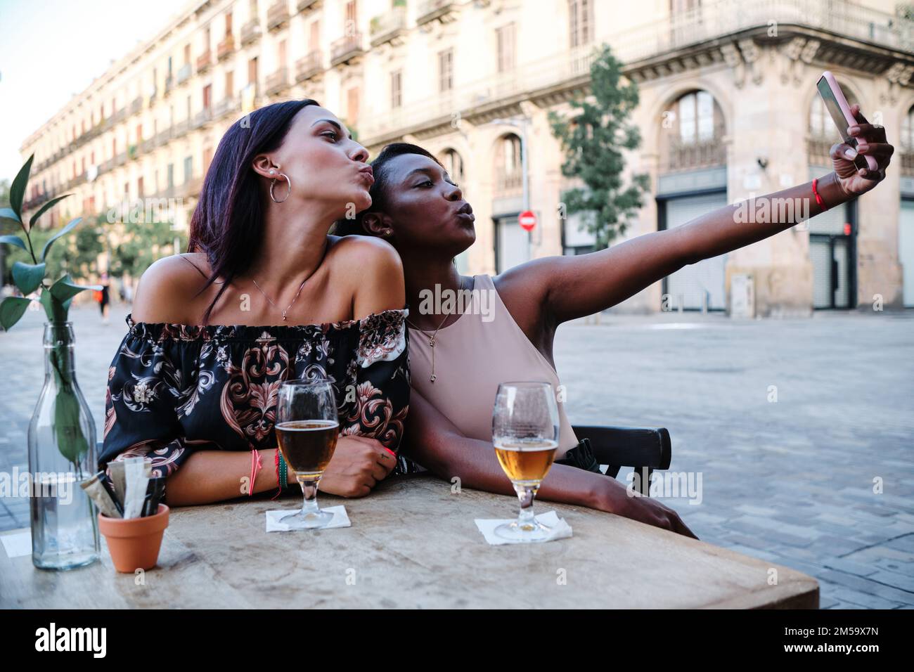 Frauen küssen sich vor der Kamera, während sie ein Selfie im Freien machen Stockfoto
