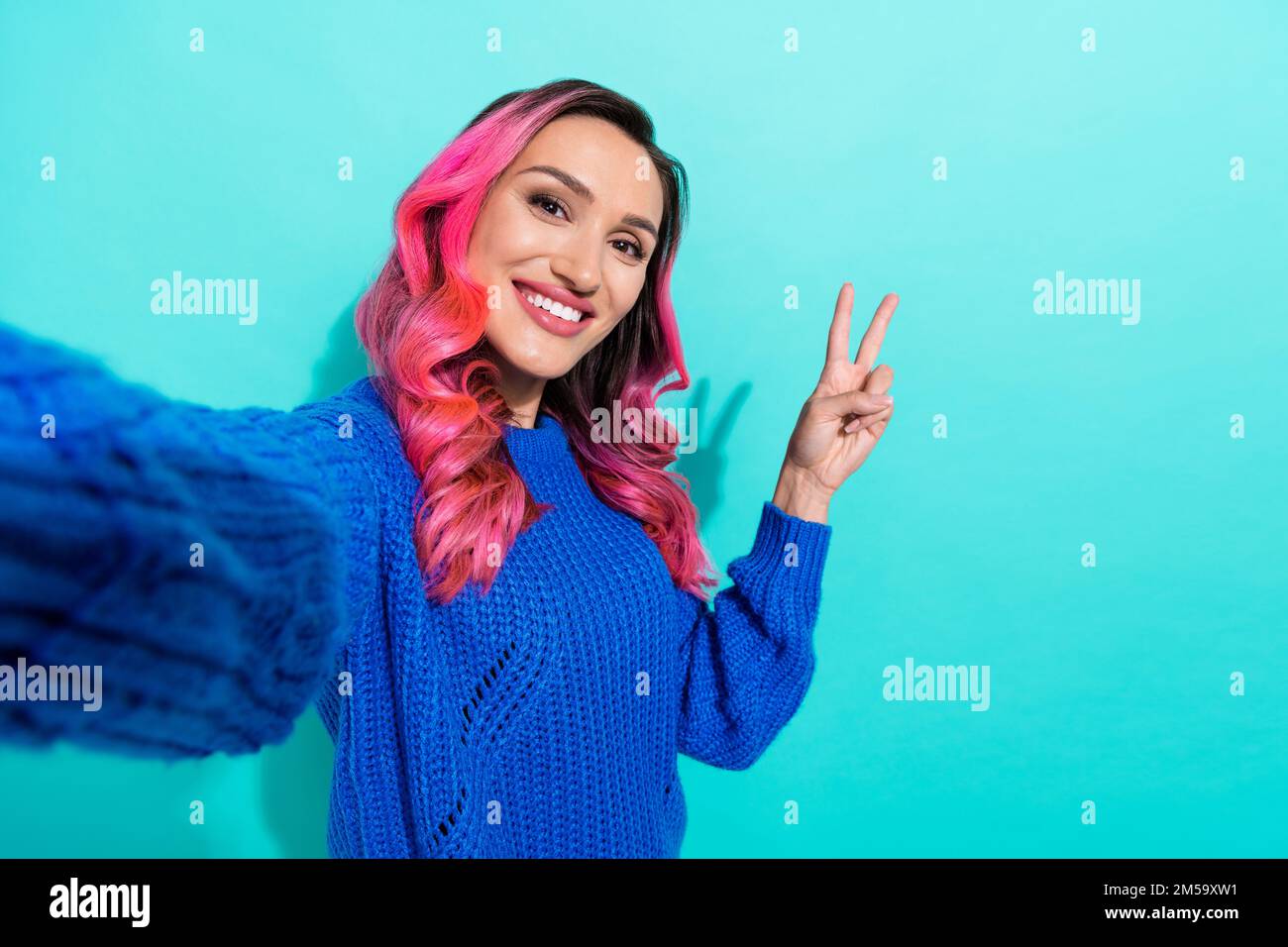 Selfie Nahaufnahme Porträtfoto des jungen Hipsters rosa gefärbtes, gewelltes Mädchen-Show V-Schild Genießen Sie den Blog-Job isoliert auf aquamarinfarbenem Hintergrund Stockfoto