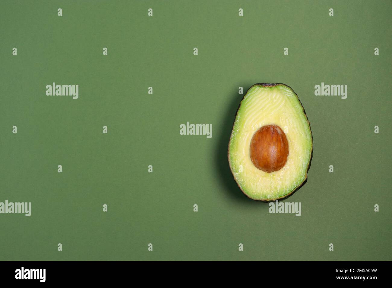 Nahaufnahme von frischer reifer Avocado auf grünem Hintergrund, Kopierbereich Stockfoto