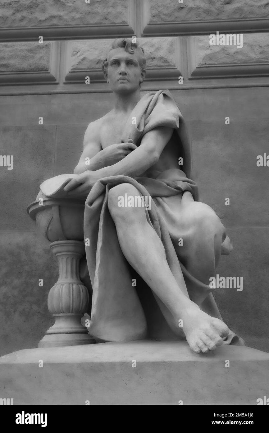 Ein vertikales Bild einer Statue eines Mannes, der am Prager Nationalmuseum sitzt und einen alten Mantel trägt Stockfoto