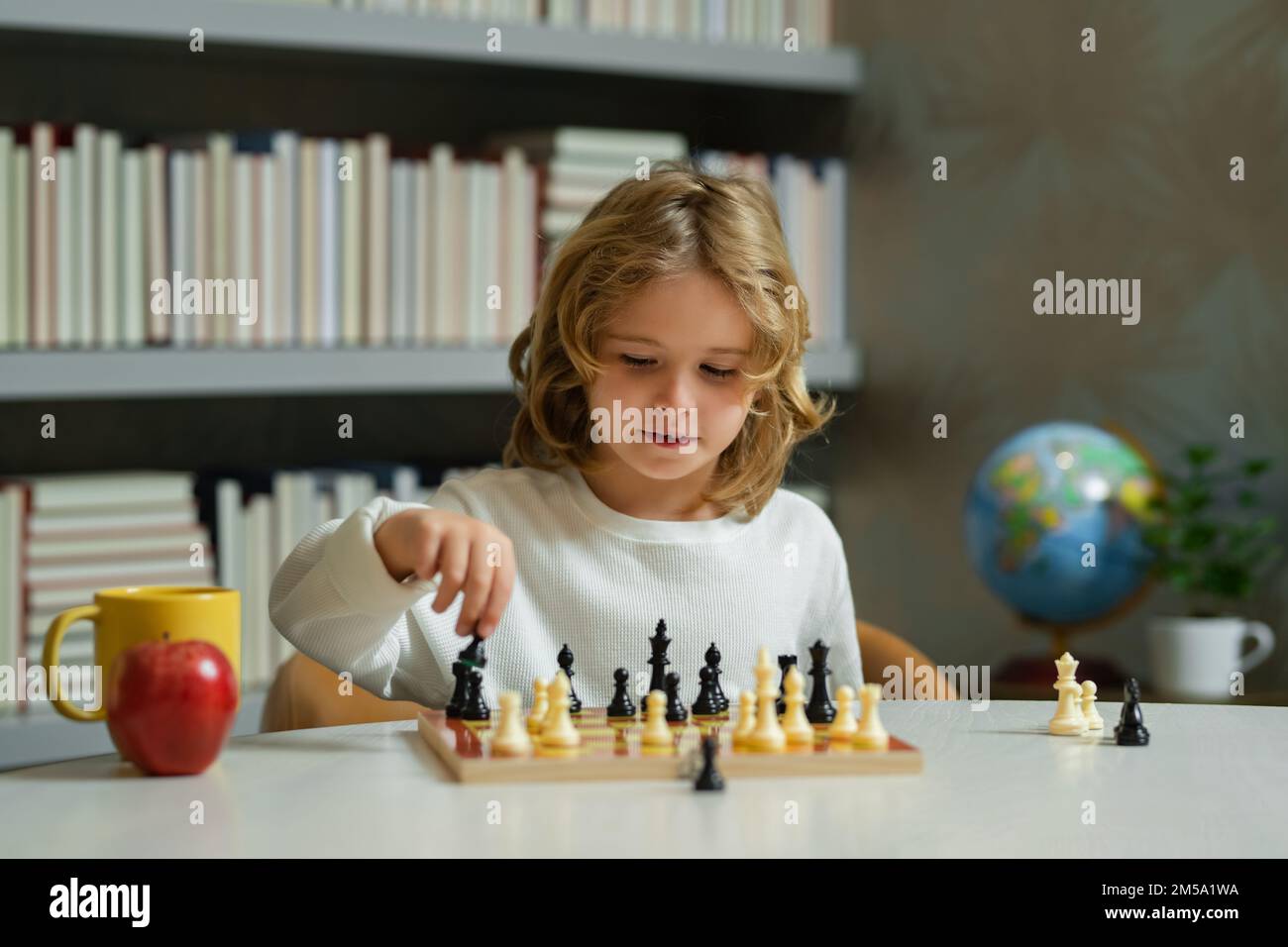 Kleines Kind spielt Schach. Kind spielt Brettspiel. Denk-Kind-Brainstorming und Idee im Schachspiel. Schachschule und Bildungskonzept. Stockfoto