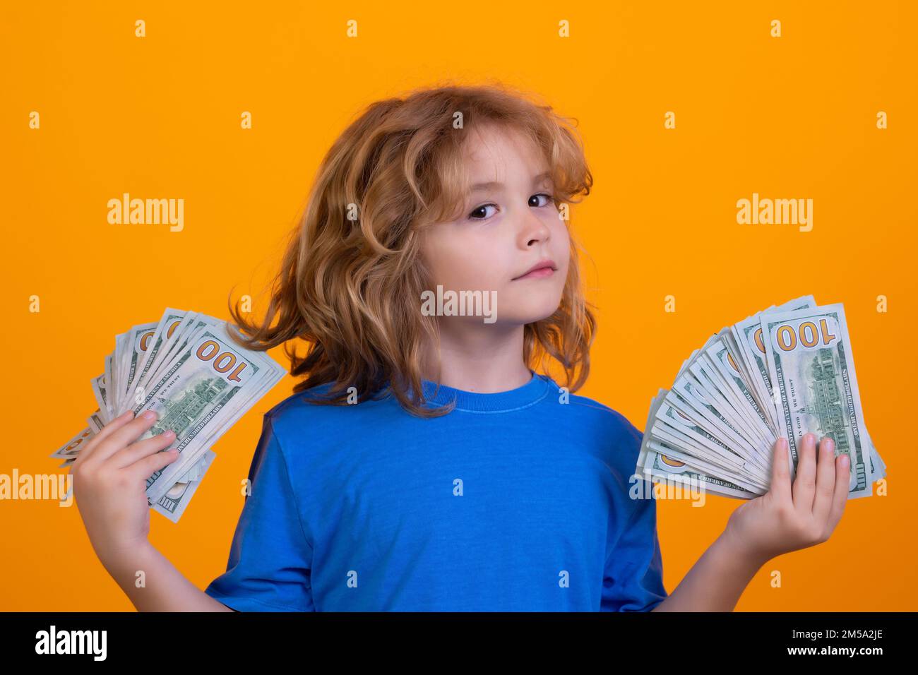 Der Junge hat viele hundert Dollar isoliert auf gelbem Hintergrund. Stockfoto