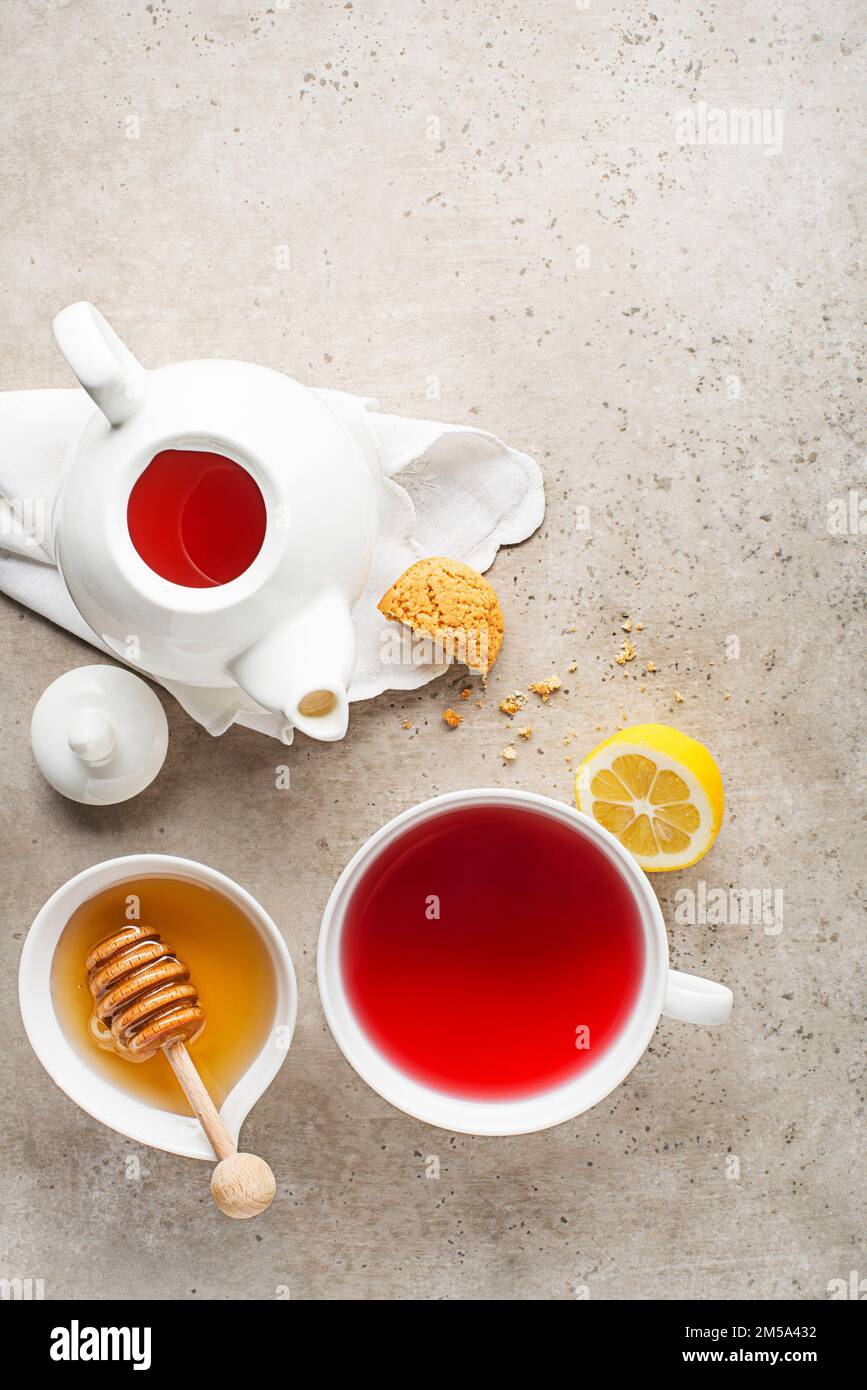 Teetasse und Teekanne mit Fruchtgeschmack, Zitrone und Honig auf grauem Tischhintergrund Stockfoto