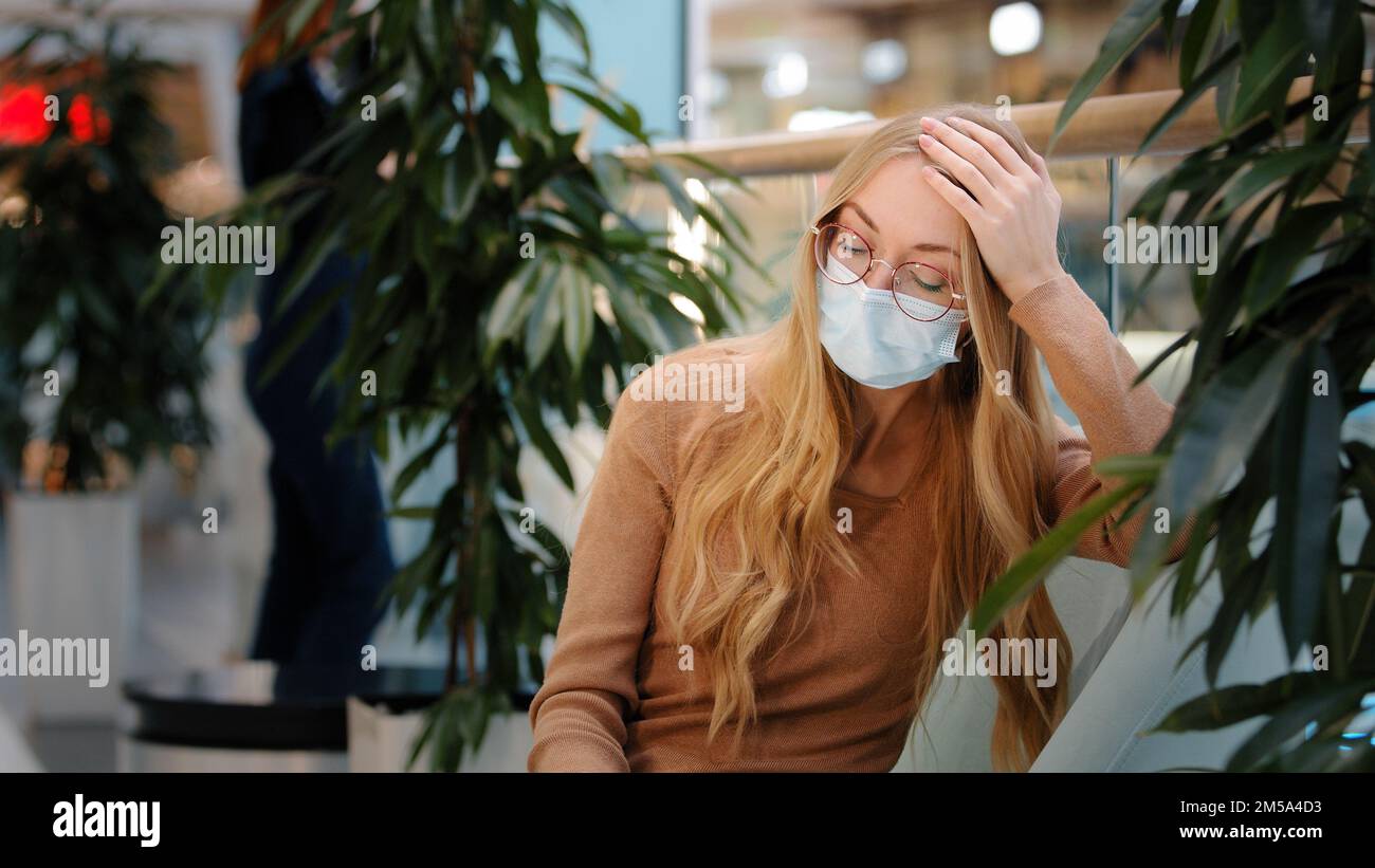 Verärgert traurig verärgert Kaukasierin in medizinische Maske mit at Smartphone unzufrieden mit schlechte Nachrichten Spam Betrug negative SMS Ablehnung App Stockfoto