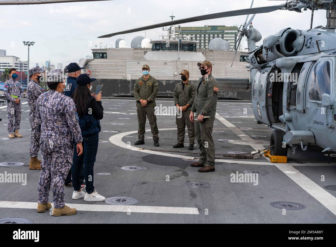 220215-N-FA490-1324 MANILA, Philippinen (15. Februar 2022) – LT. Garrett Schafer, rechts, vom State College, Pennsylvania, angeschlossen an Helicopter Sea Combat Squadron (HSC) 23, zugewiesen an das Küstenschiff USS Jackson (LCS 6), beantwortet Fragen zu einem MH-60s Hubschrauber von           Auf dem Flugdeck von Jackson. Im Anschluss an die Destroyer Squadron (DESRON) 7 befinden sich Jackson und HSC-23 in einem Rotationseinsatz in das US-7.-Flottengebiet, um die Sicherheit und Stabilität in der Region zu unterstützen und mit den alliierten und Partnerschifffahrtsleuten zusammenzuarbeiten, um die Seeschifffahrt zu gewährleisten Stockfoto