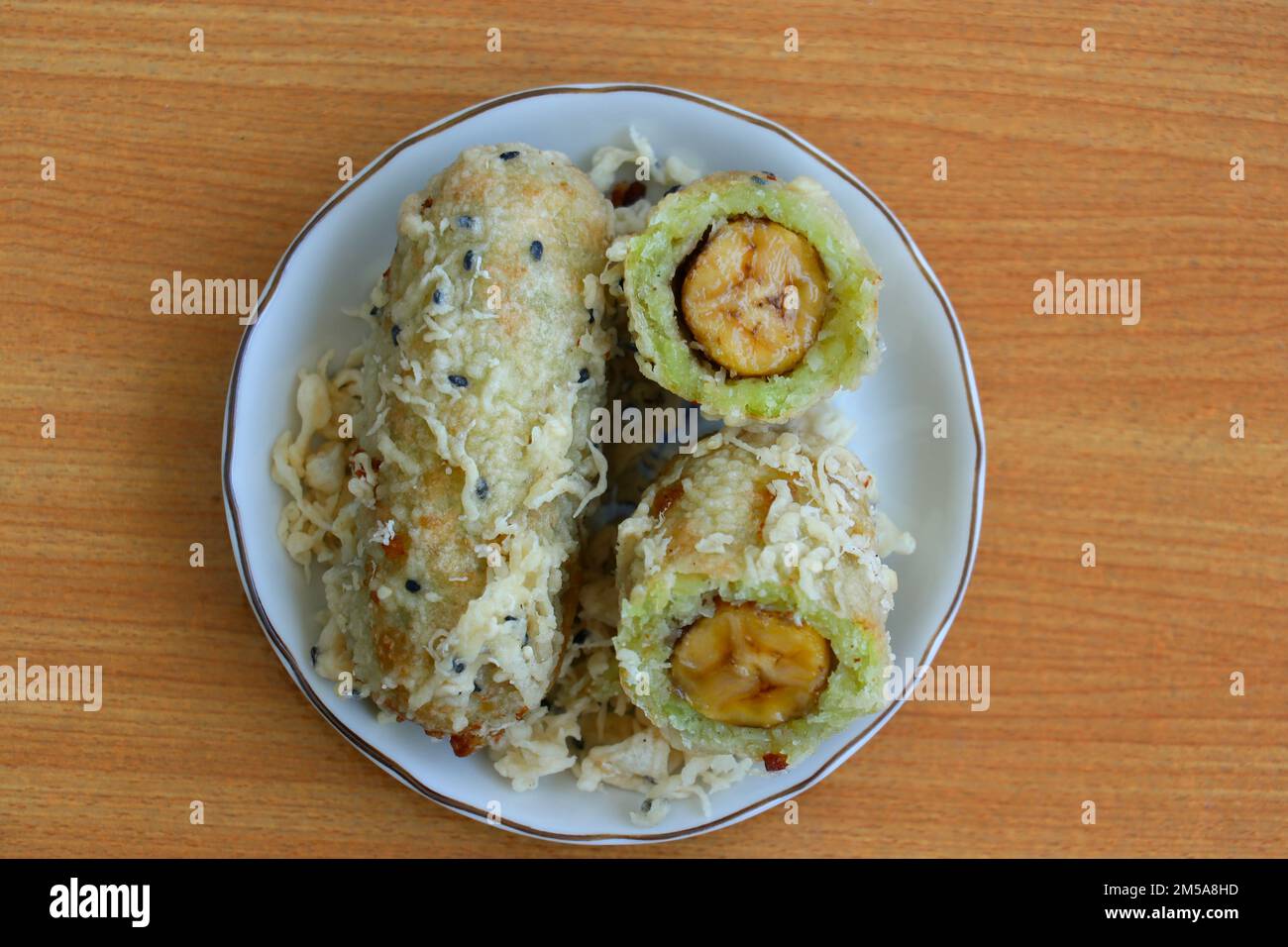 Zerkleinerter und frittierter, unreifer Reis und geriebene Kokosnuss-Bananenrollen Stockfoto
