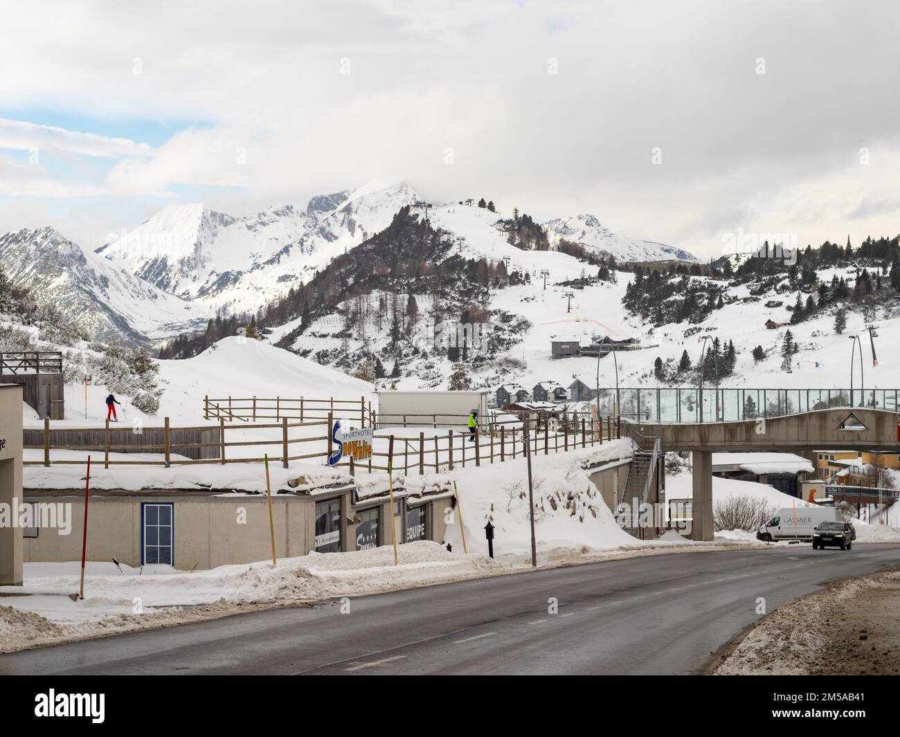 Blick auf die Römerstraße mit den europäischen Alpen im Hintergrund. Wunderschöne Landschaft mit großen Bergen und schneebedeckten Gipfeln. Menschen und Gebäude. Stockfoto