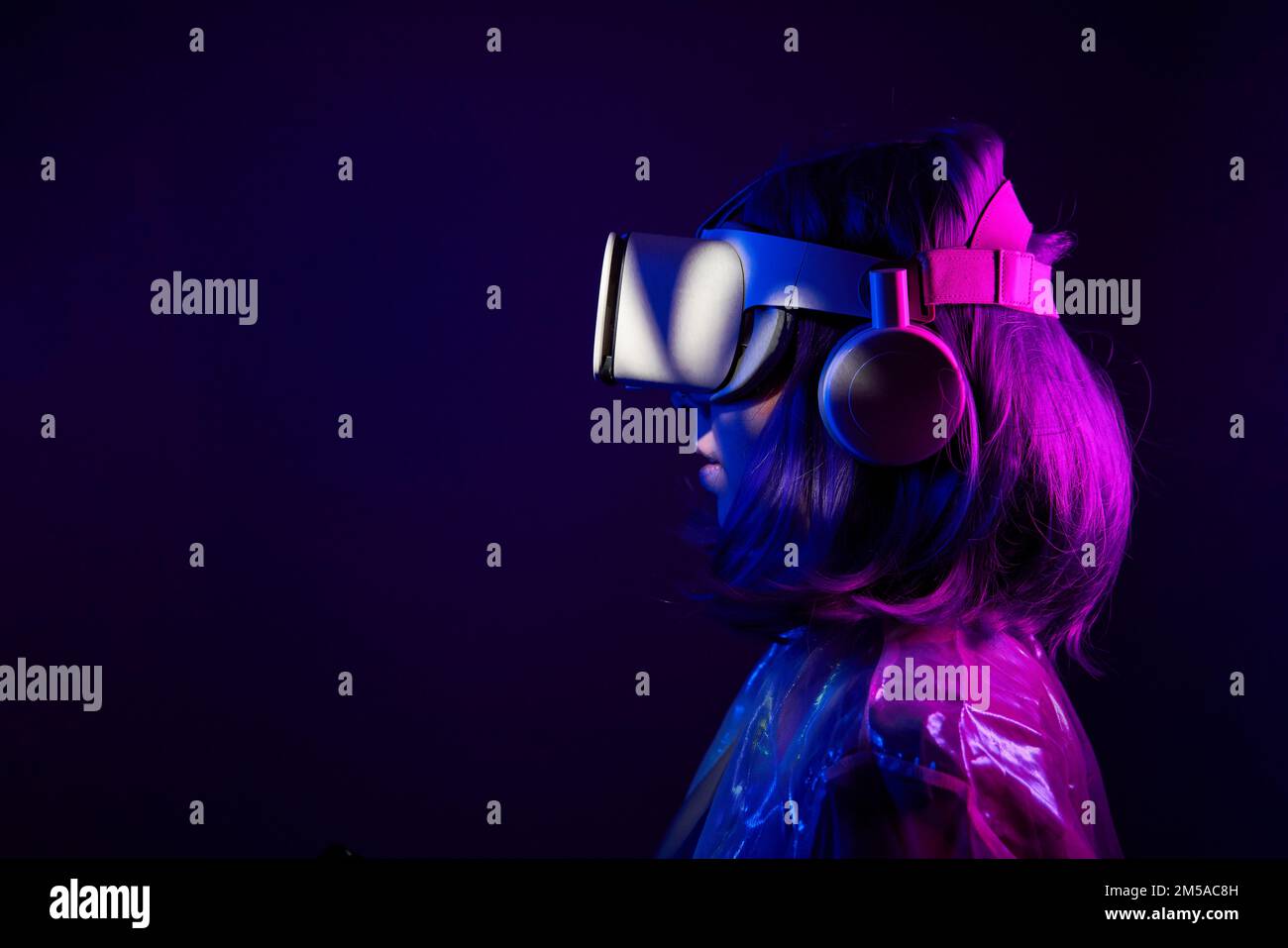 Eine Frau in Virtual-Reality-Brille in Neonfarben. Das Konzept der digitalen Technologie für Metaversum und Unterhaltung der Zukunft. Stockfoto