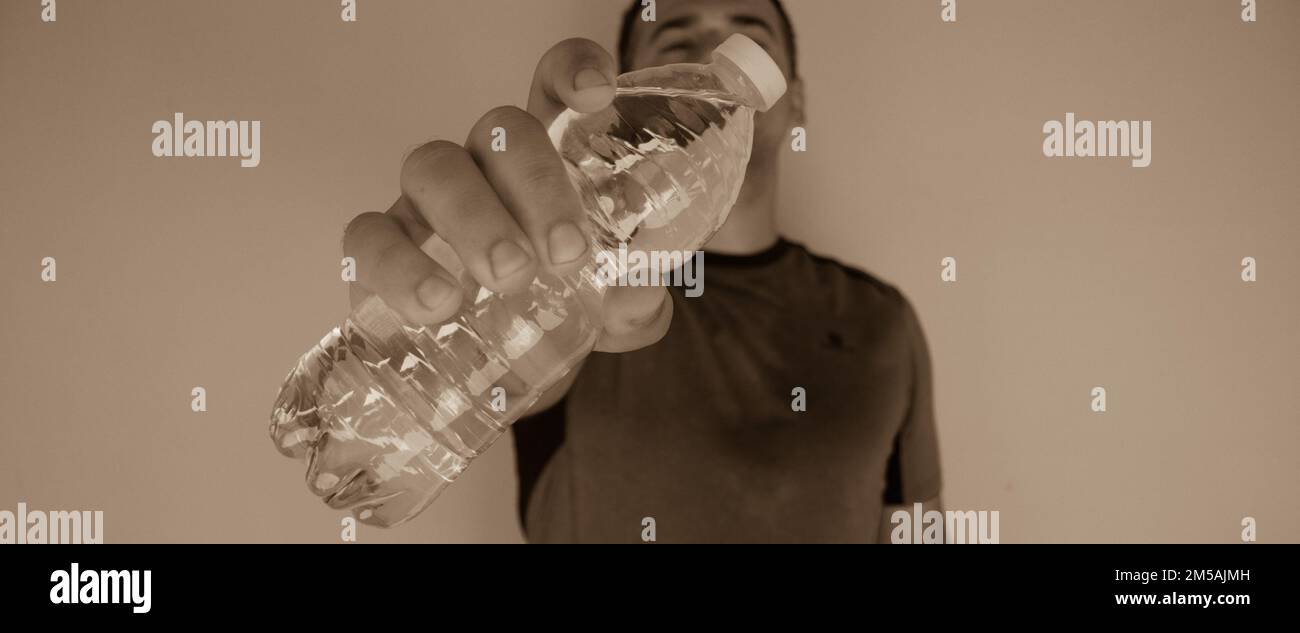 Bild eines Mannes, der nach dem Sport eine Flasche Wasser öffnet. Rehydratation des Körpers. Horizontales Banner Stockfoto