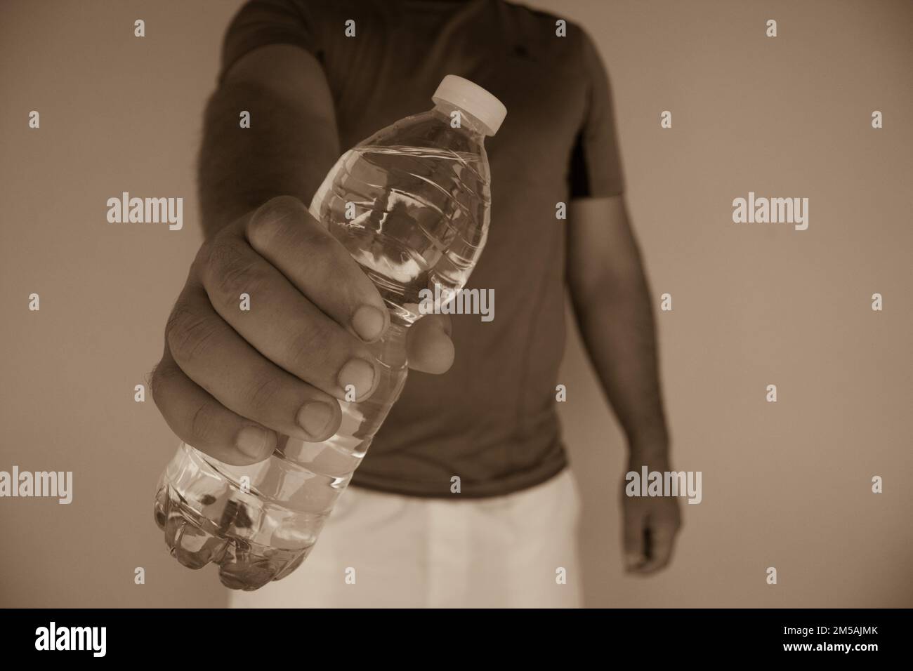 Bild eines Mannes, der nach dem Sport eine Flasche Wasser öffnet. Rehydratation des Körpers Stockfoto