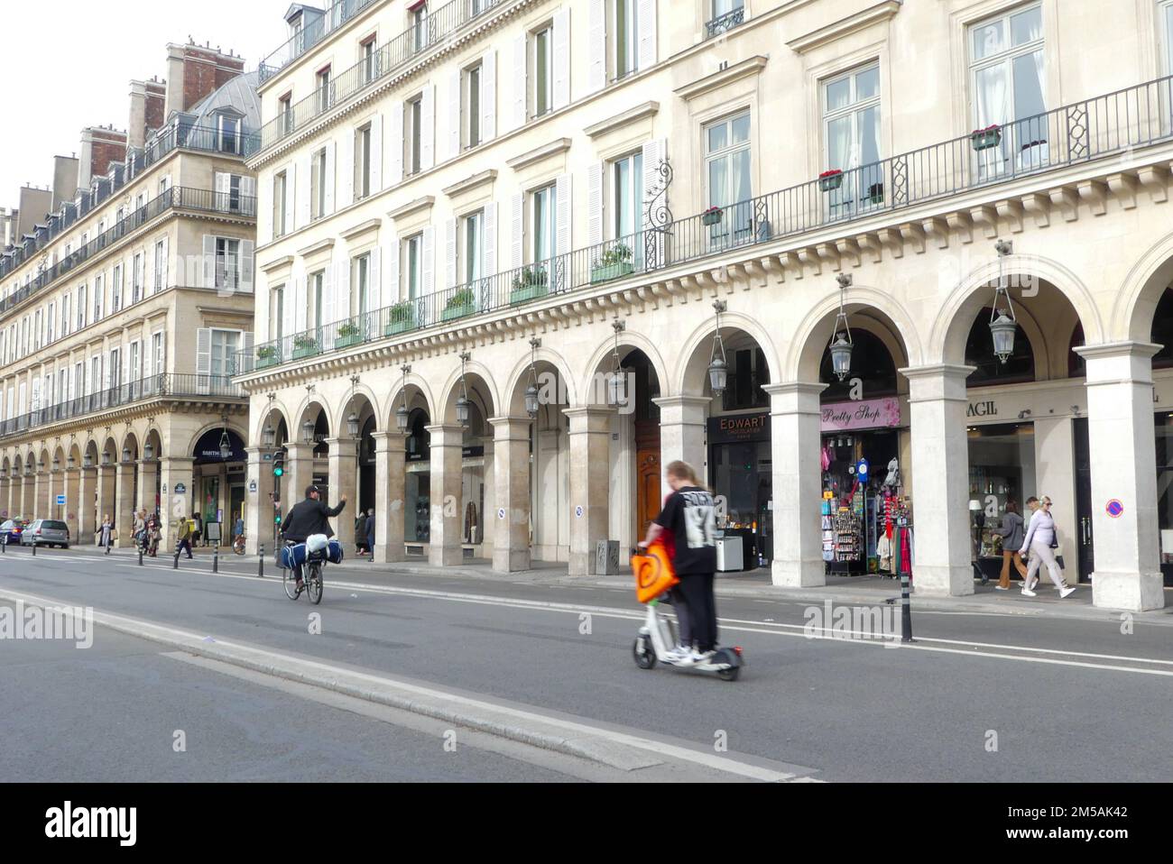 Paris, Frankreich. Oktober 30. 2022. Blick auf Gebäude im Haussmann-Stil in der berühmten Rue de Rivoli mit Menschen auf einem elektrischen Roller. Stockfoto